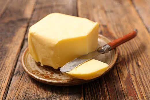 Piatto di burro con coltello su tavolo in legno.